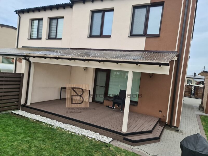 Stoginė su šviesiomis kolonomis prie dviaukščio namo